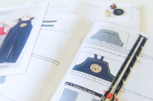 Kids overalls sewing pattern in denin. Instructions are open to read.