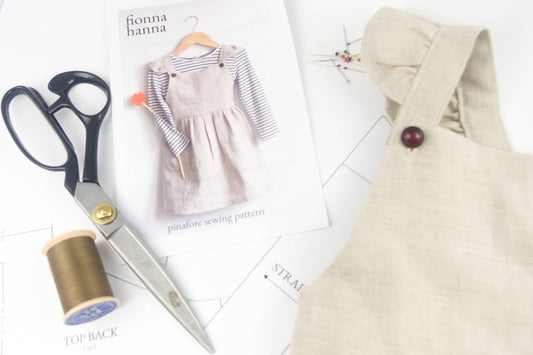 pinafore dress pattern with scissors, thread and pattern